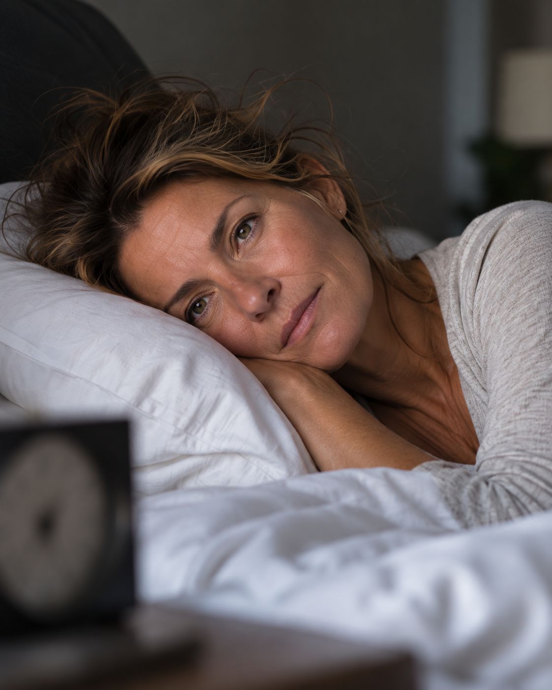 Frau Anfang fünfzig liegt nachts wach im Bett